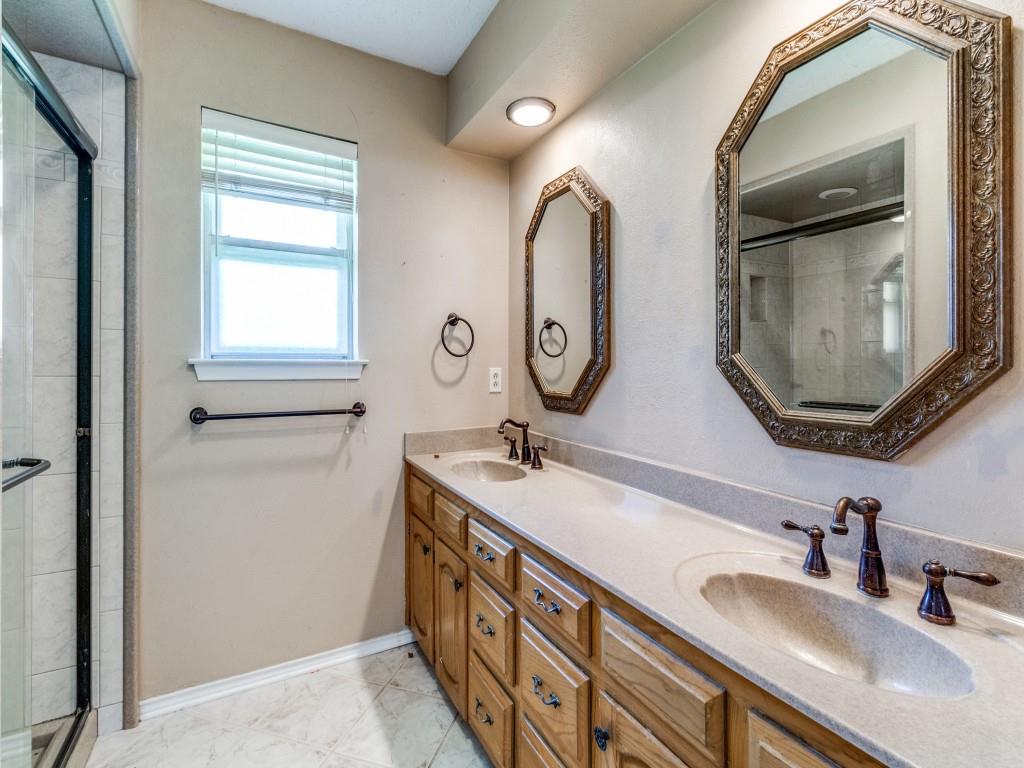 Primary bathroom featuring a shower stall, double vanity, and marble finish floors