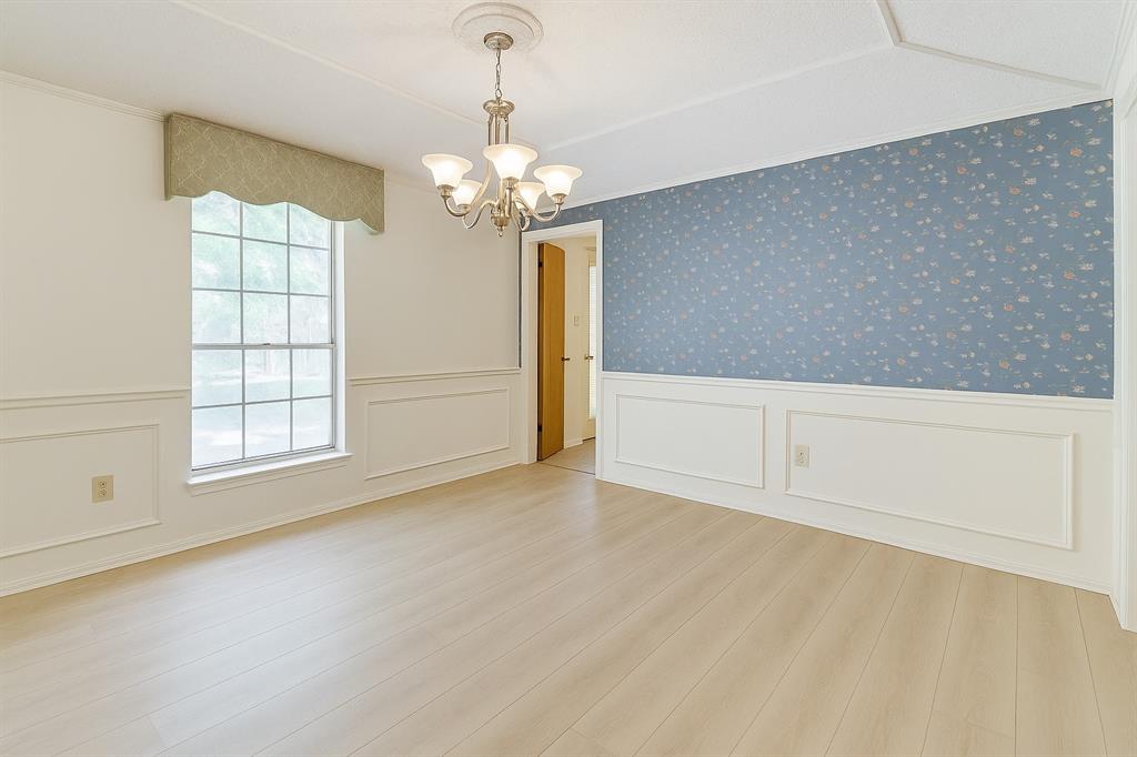 Dining room with a chandelier, a wainscoted wall, wood finished floors, and crown molding