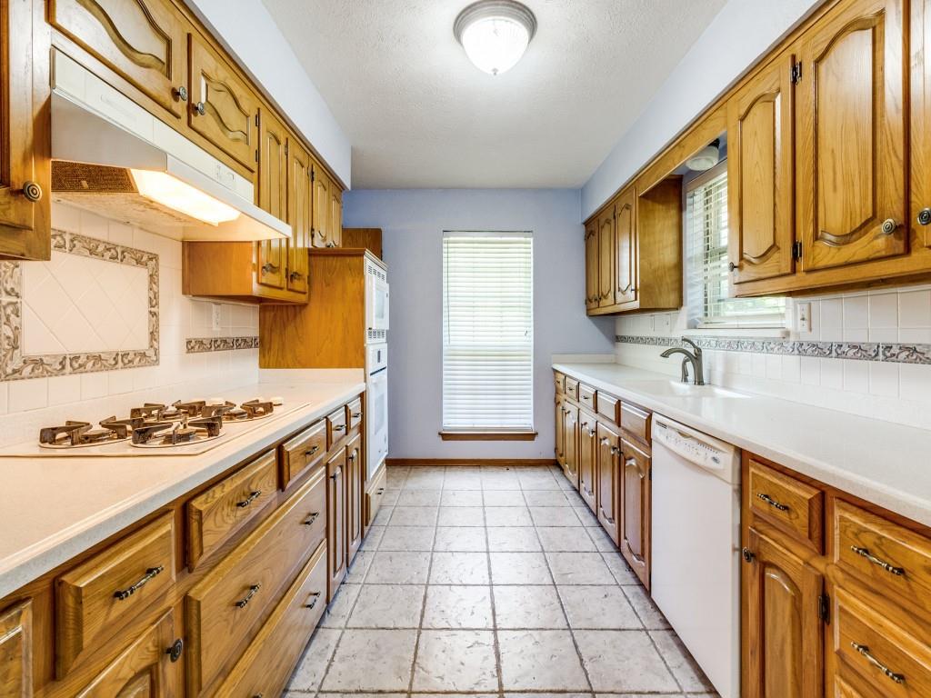 Kitchen with white appliances, under cabinet range hood, tasteful backsplash, baseboards, and a textured ceiling