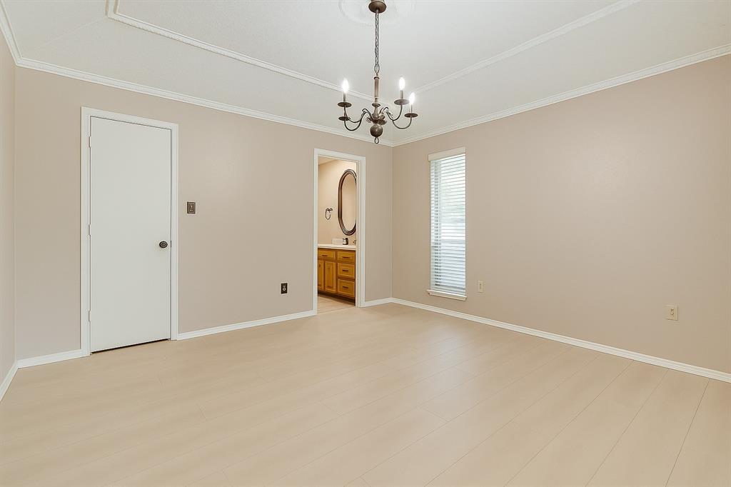 Primary bedroom featuring a chandelier, crown molding, and baseboards