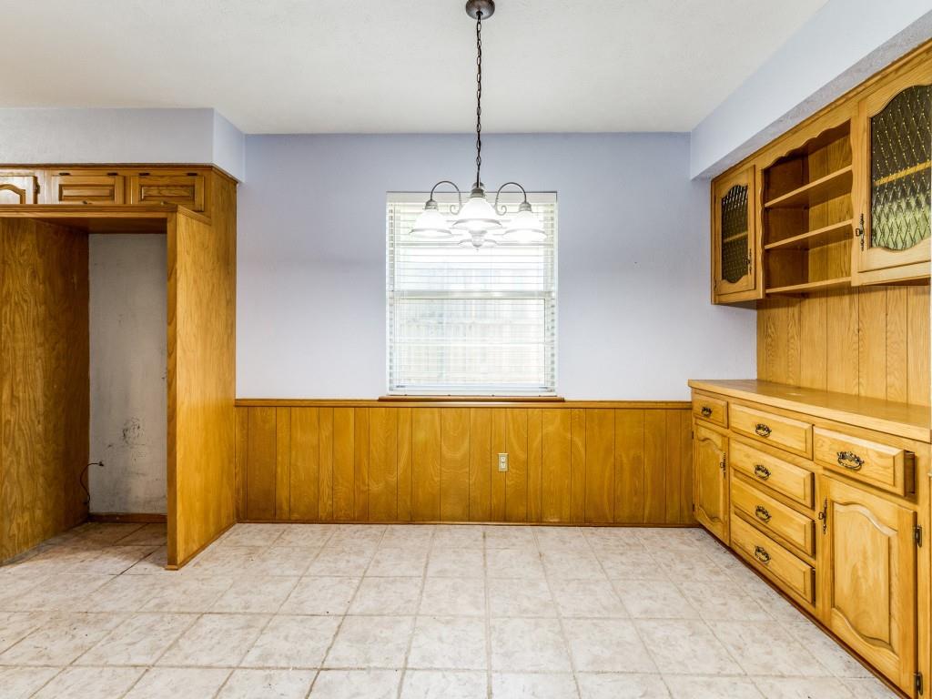 Unfurnished dining area with a wainscoted wall, wood walls, and a chandelier