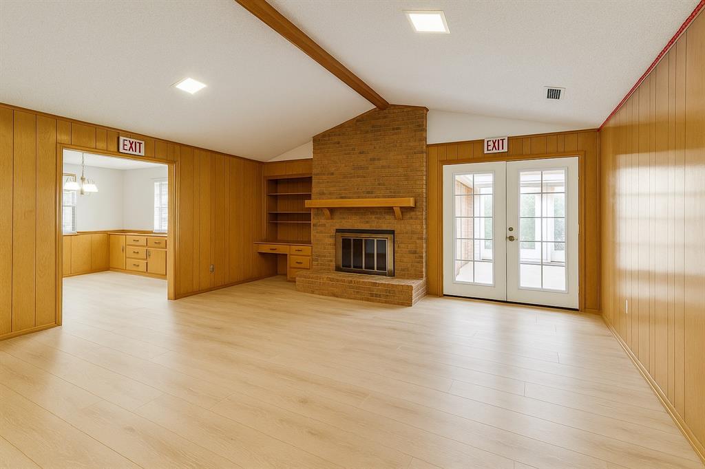 Unfurnished living room featuring wood walls, light wood-type flooring, a fireplace, and french doors