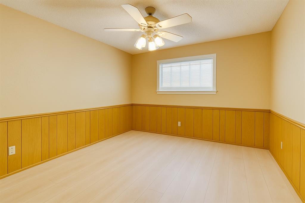Unfurnished bedroom featuring a wainscoted wall, wood finished floors, and ceiling fan