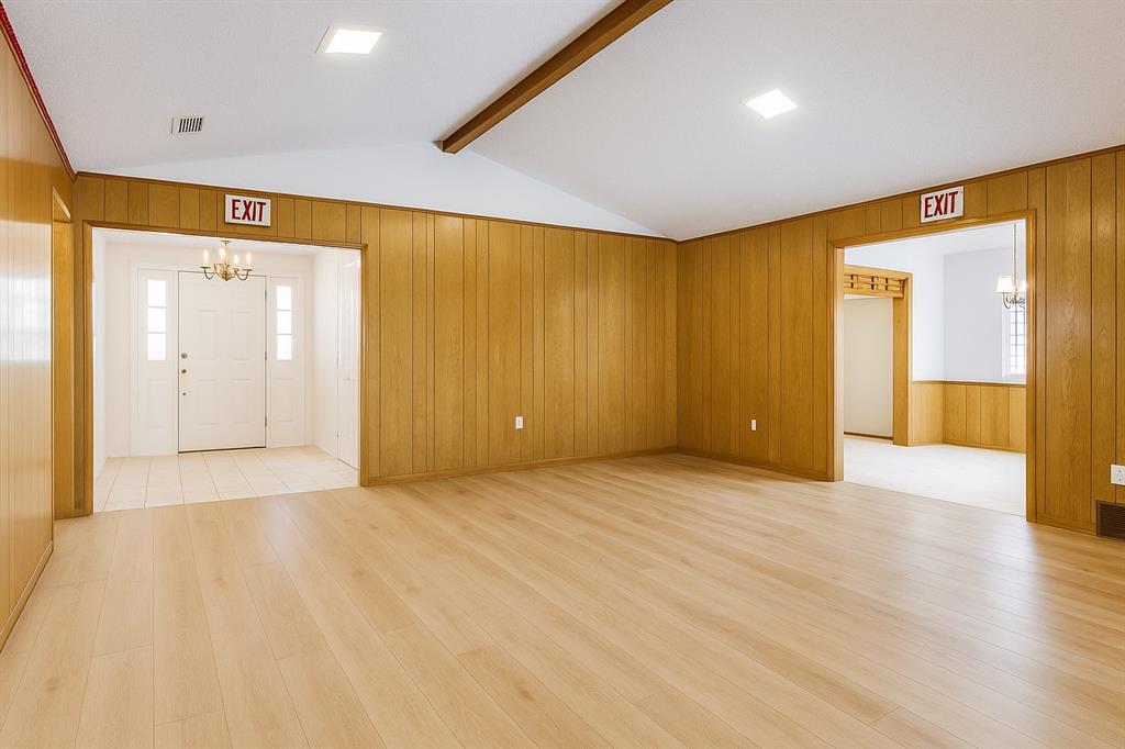 Entrance foyer featuring a chandelier, wooden walls, light wood finished floors, and healthy amount of natural light
