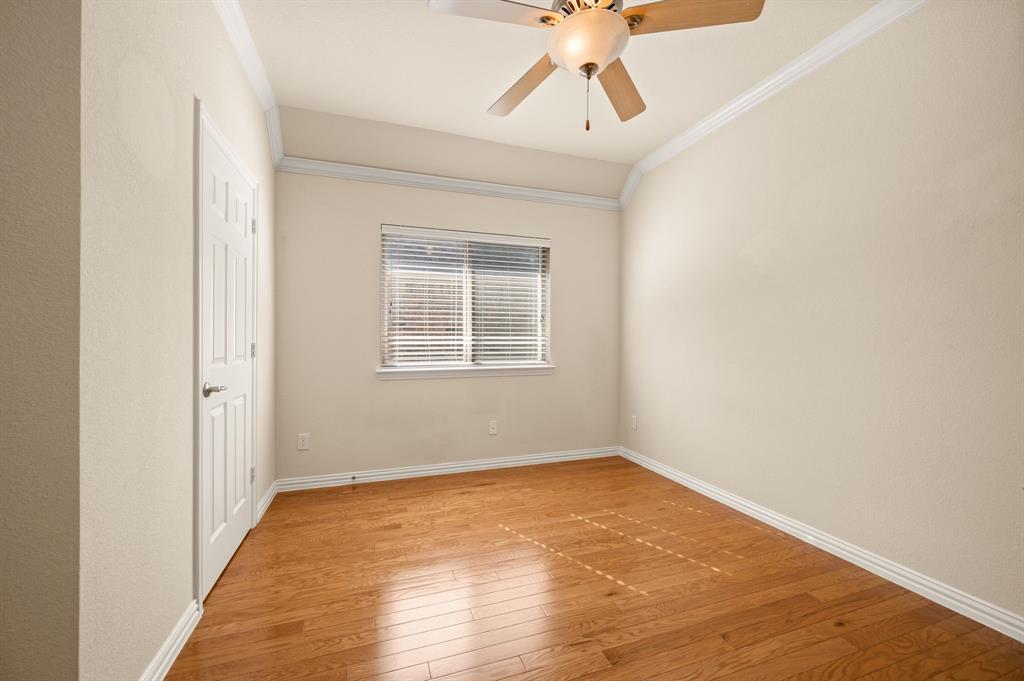 Room featuring wood-finish flooring, vaulted ceilings with crown molding, and a central ceiling fan with an integrated light fixture
