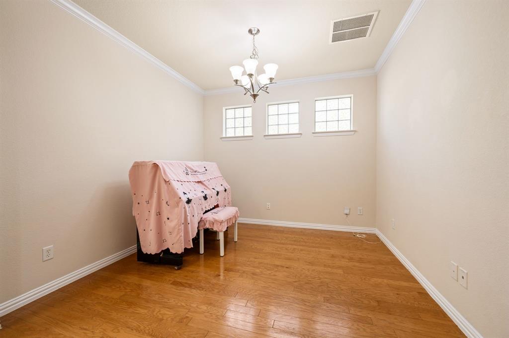 Interior space featuring wood-finish flooring, crown molding, a multi-light chandelier, and three transom-style windows