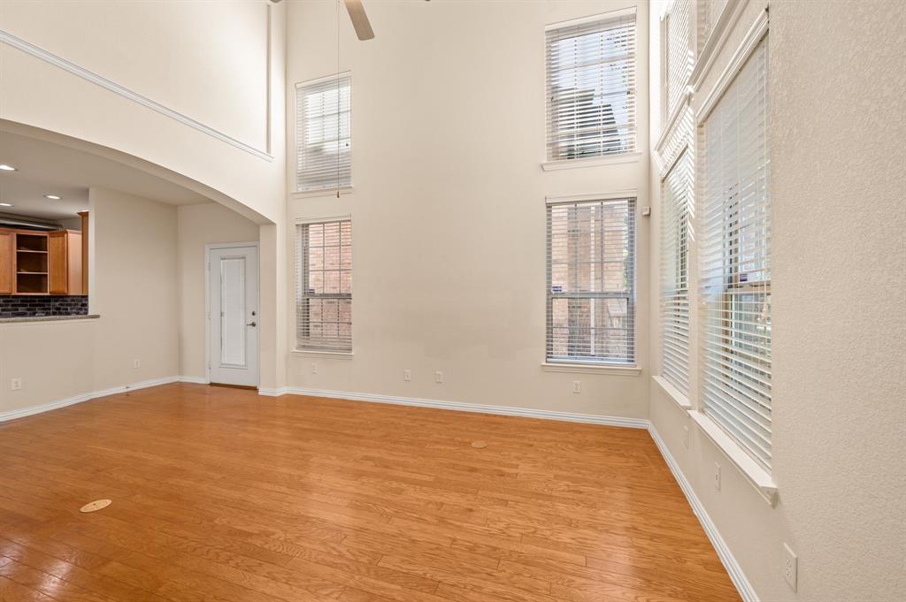 High-ceiling room featuring wood-finish flooring, multi-level windows, and crown molding