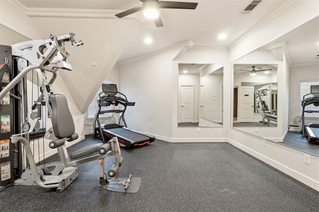 Dedicated exercise space featuring durable rubber flooring, wall-mounted mirrors, and an angled ceiling