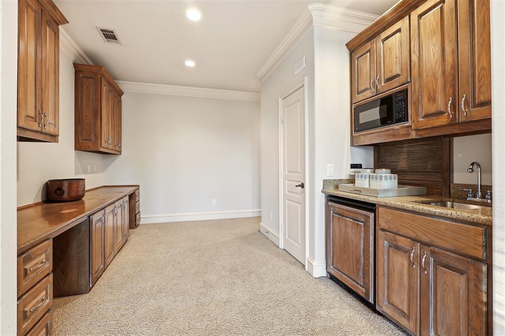 Built-in cabinetry with wood-finish, recessed lighting, crown molding, integrated microwave, and a wet bar with a sink