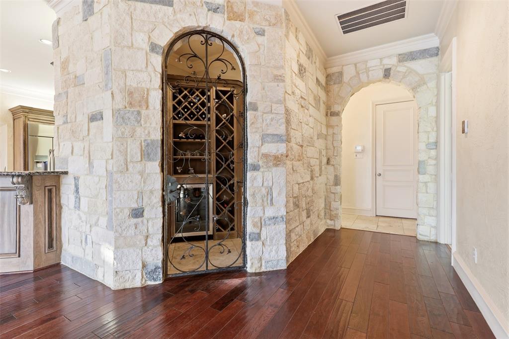 Stone accent wall with an arched entryway and a built-in wine cellar featuring a wrought iron gate