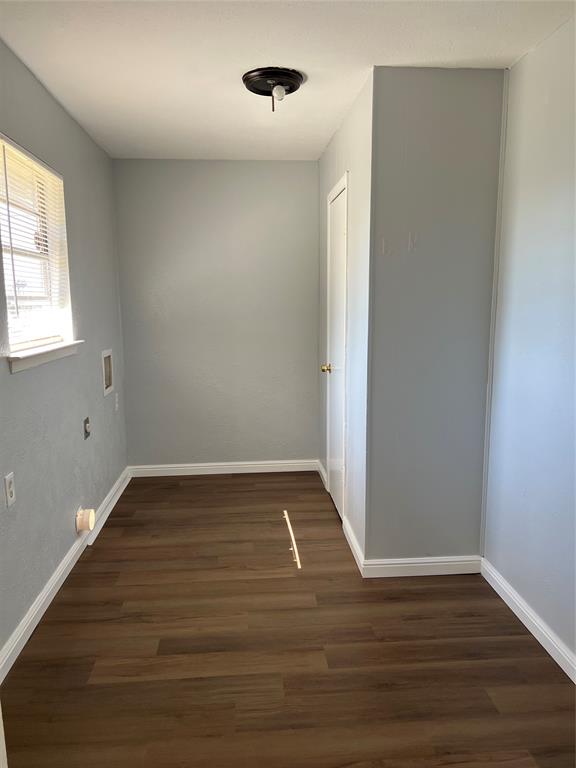 Interior space featuring wood-finish flooring, a single-pane window, flush-mount lighting, and a solid-core interior door Interior space featuring wood-finish flooring, a single-pane window, flush-mount lighting, and a solid-core interior door