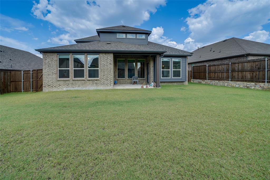 Rear view of house with a patio, a fenced backyard, brick siding, and a shingled roof