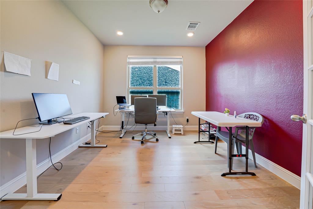 Home office with light wood-style flooring, a textured wall, and recessed lighting