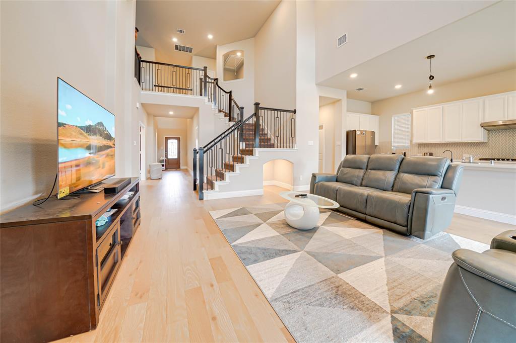Living room with a high ceiling, light wood finished floors, recessed lighting, and stairs