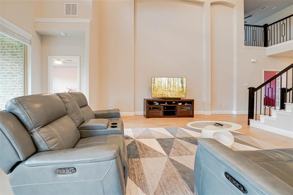 Living room with a ceiling fan, light wood finished floors, stairway, and a towering ceiling