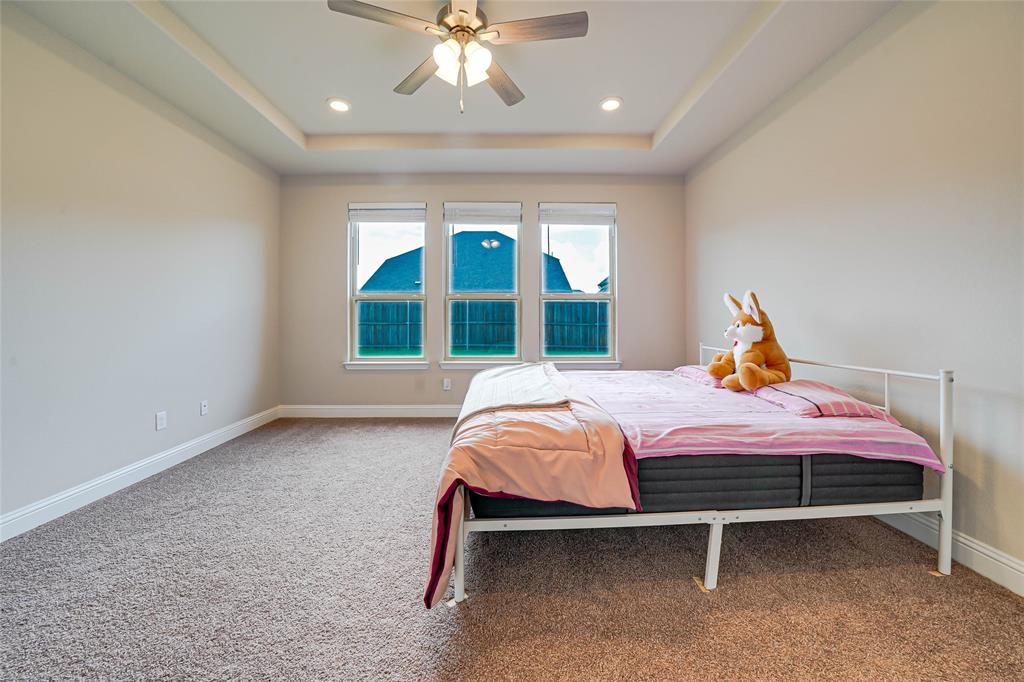 Carpeted bedroom with a ceiling fan, a tray ceiling, and recessed lighting