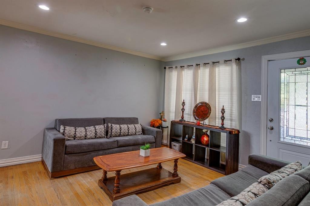 Living area featuring wood-finish flooring, recessed lighting, crown molding, and an exterior door with decorative glass paneling