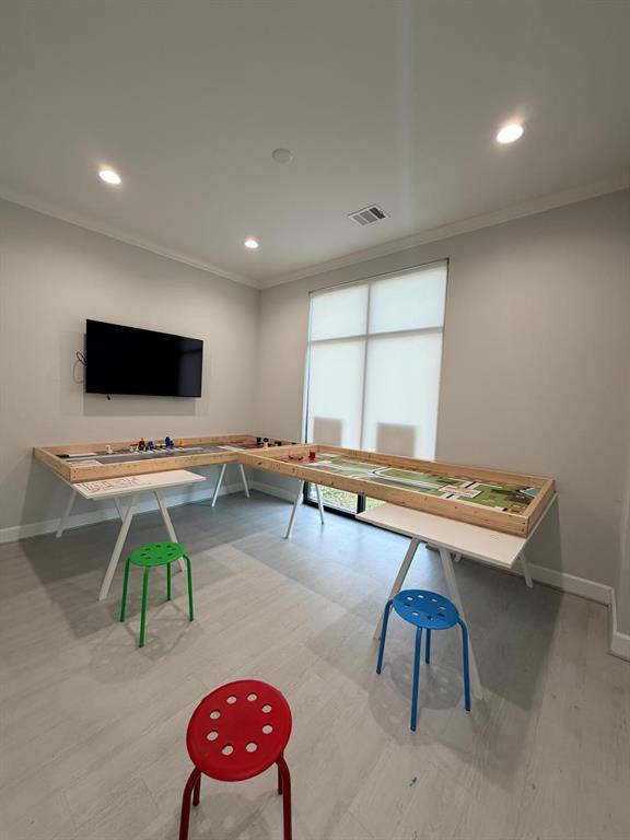 Room featuring neutral-toned walls, wood-finish flooring, recessed lighting, and a large window with a roller shade