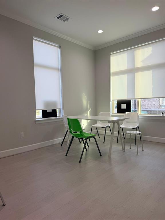 Neutral-toned interior space featuring wood-finish flooring, recessed lighting, and large windows with integrated roller shades