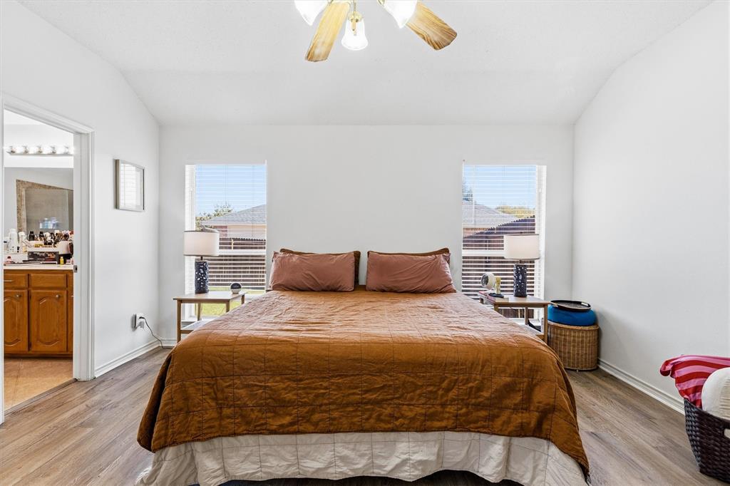 The primary bedroom features dual windows, raised ceilings, ceiling fan and updated flooring