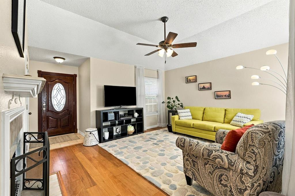 Warm and inviting living room with laminate flooring, ceiling fan, and gas log fireplace. Warm and inviting living room with laminate flooring, ceiling fan, and gas log fireplace.