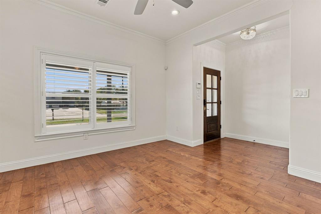 Interior space featuring wood-finish flooring, white plantation shutters, crown molding, a ceiling fan, and a wood-framed glass-paneled entry door