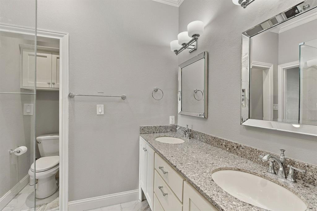 Double vanity with stone countertop, dual undermount sinks, white cabinetry, and polished chrome fixtures