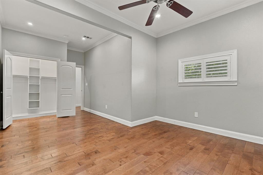 Room featuring wood-finish flooring, recessed ceiling lighting, a multi-blade ceiling fan, and a walk-in closet with built-in shelving