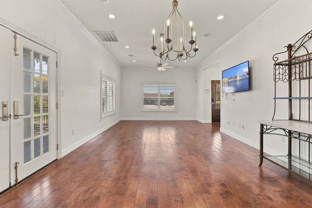 Open living area featuring wood-finish flooring, crown molding, recessed lighting, a chandelier, and double French doors with glass panes