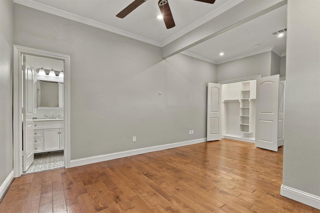 Wood-finish flooring, crown molding, ceiling fan, and built-in closet shelving