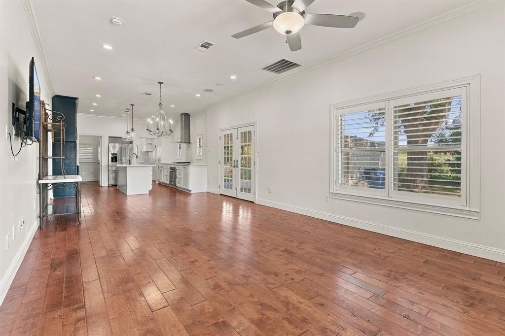Open-concept interior featuring wood-finish flooring, recessed lighting, a dual-lighted ceiling fan, plantation shutters, and glass-paned French doors