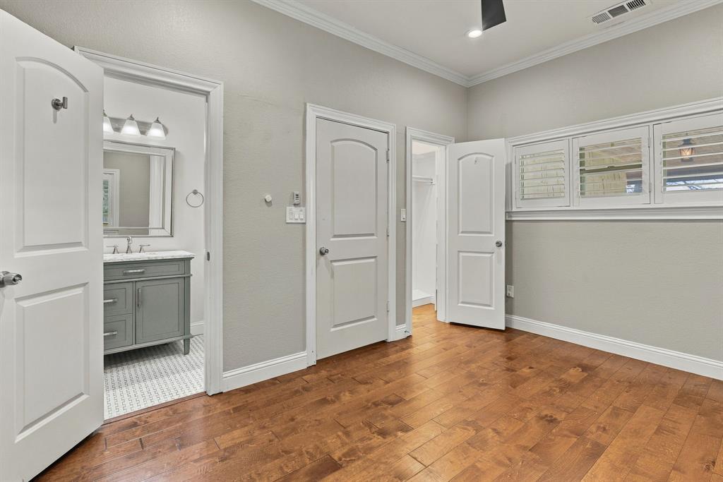 Room with wood-finish flooring, crown molding, multi-panel doors, and windows featuring plantation shutters
