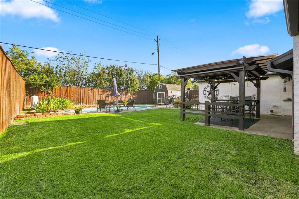 Private backyard featuring a swimming pool, covered wooden pergola, wood privacy fencing, and a detached storage structure