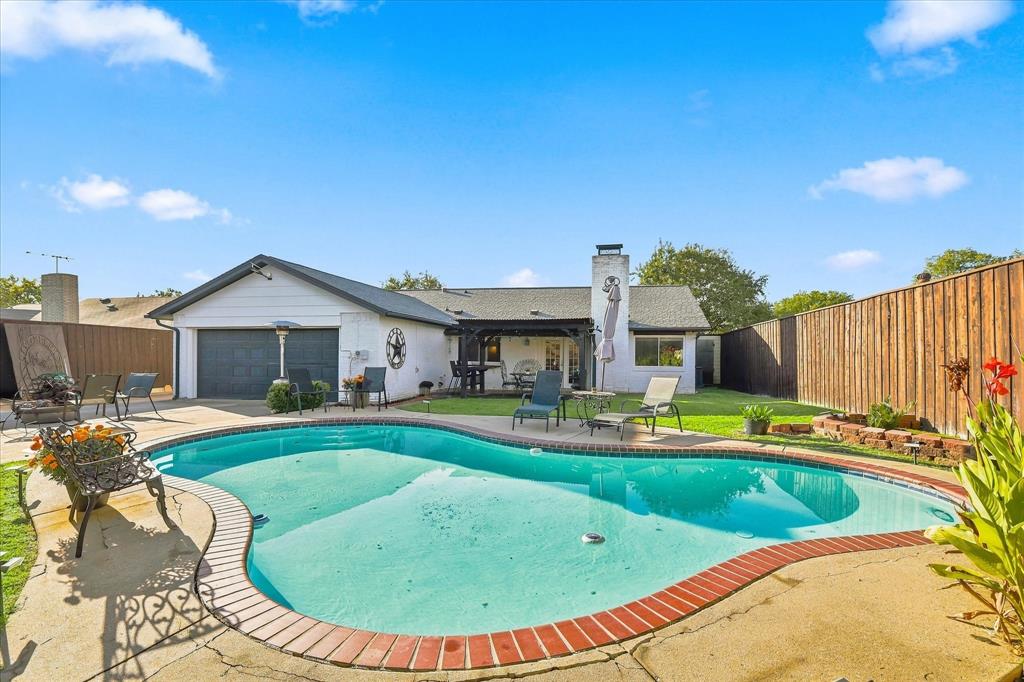 Backyard featuring an in-ground swimming pool with brick coping, a concrete deck, a covered patio, and wood privacy fencing