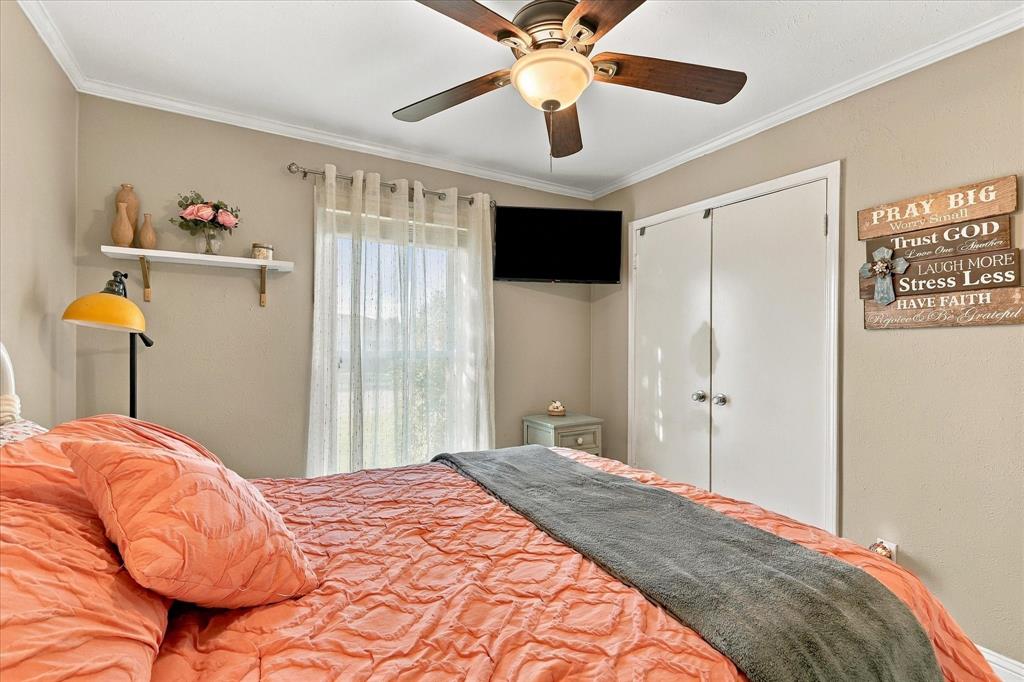 Room featuring a ceiling fan with integrated lighting, a single wall-mounted shelving unit, and a double-door reach-in closet