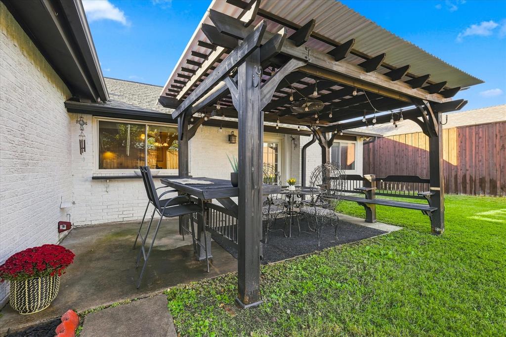 Covered patio featuring a timber-frame pergola, concrete flooring, and exterior brick siding