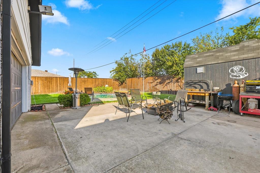 Backyard featuring a concrete patio, inground pool, wood perimeter fencing, and a detached storage structure