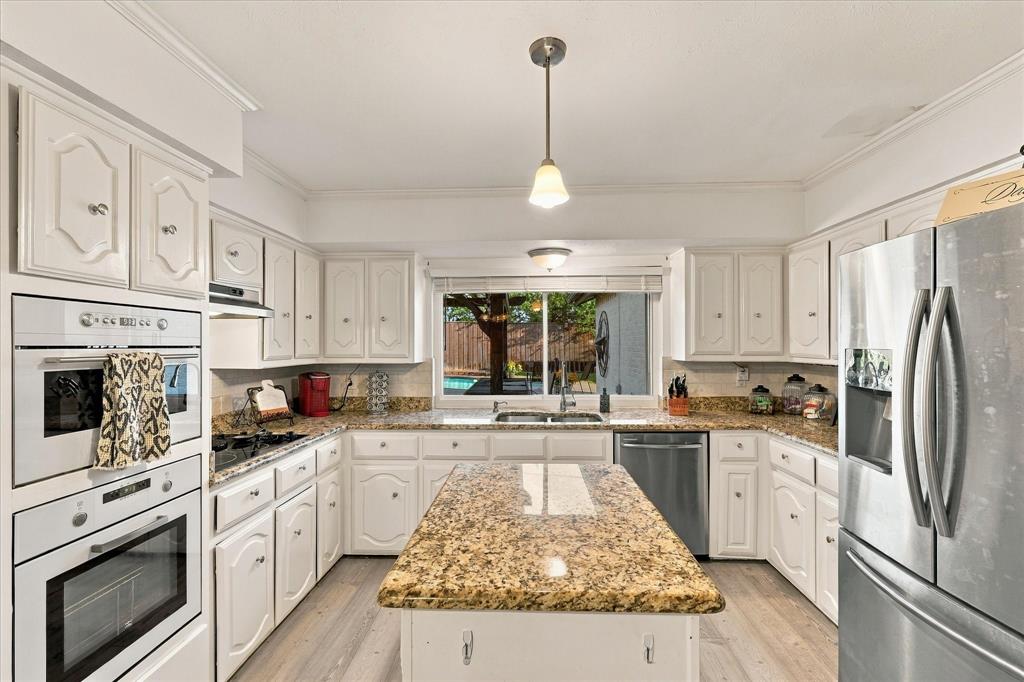 Kitchen featuring white cabinetry, stone countertops, a central island, stainless steel appliances, and wood-finish flooring