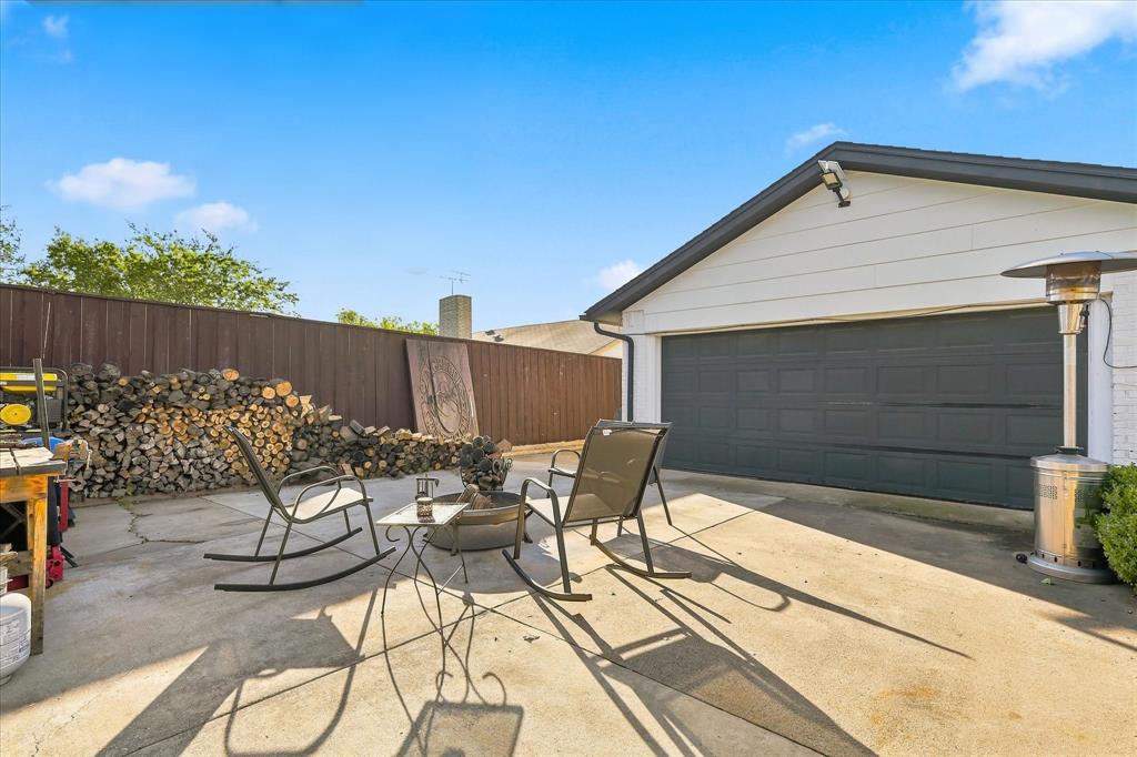 Concrete patio area featuring a detached garage with a paneled door and enclosed by wood fencing
