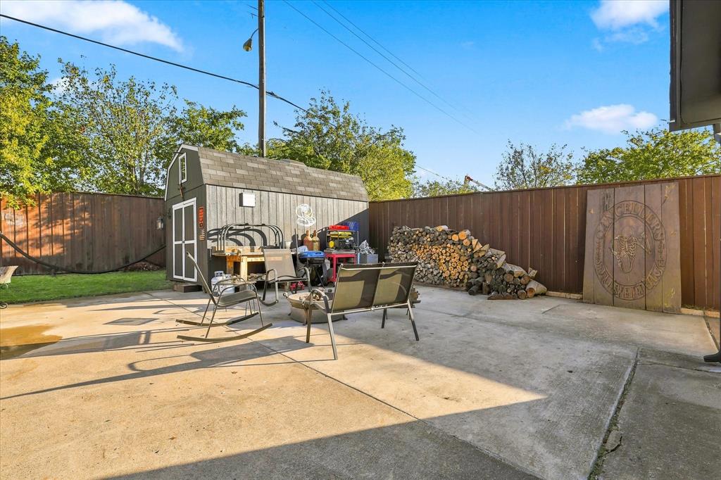 Concrete patio featuring a detached storage shed and wood privacy fencing