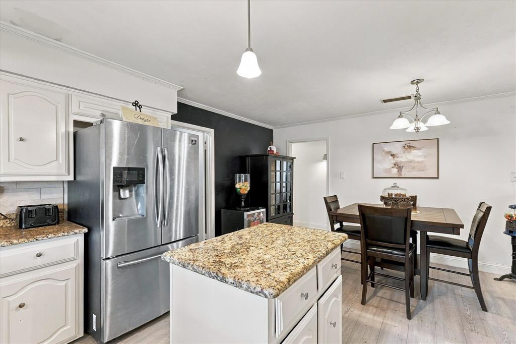 Kitchen featuring white cabinetry, stone-finish countertops, stainless steel refrigerator, center island, and wood-finish flooring