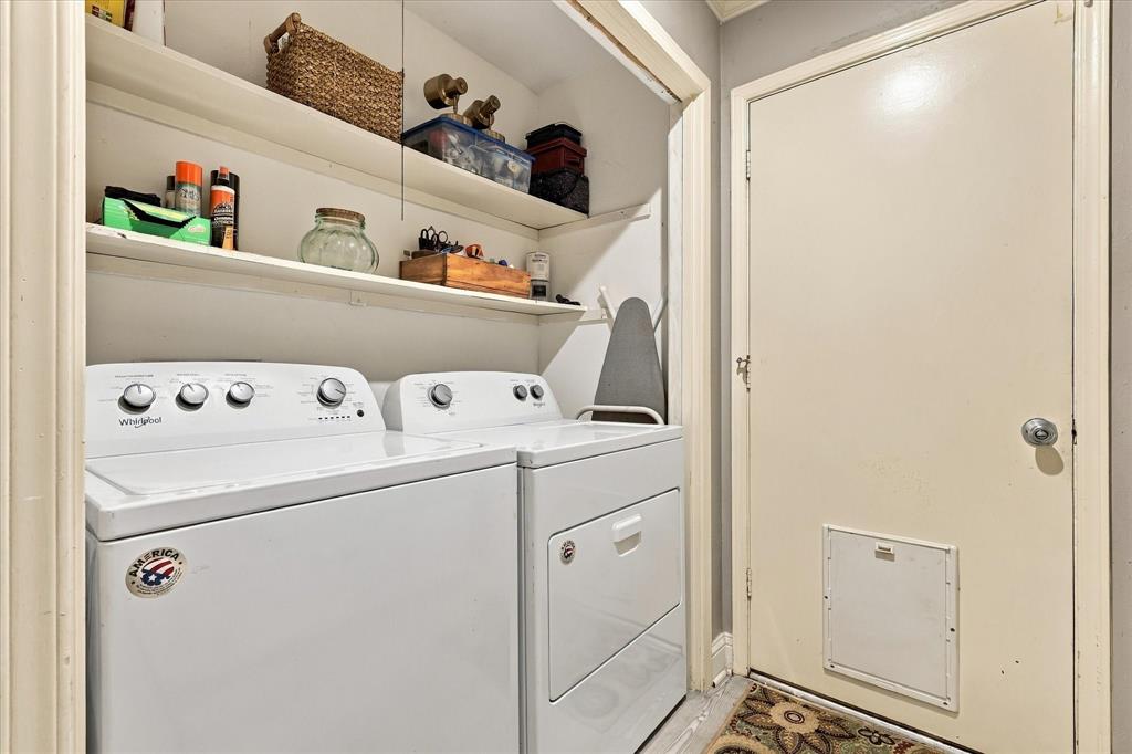 Laundry area featuring two levels of built-in shelving, white laundry appliances, and a solid-core door with a built-in pet portal