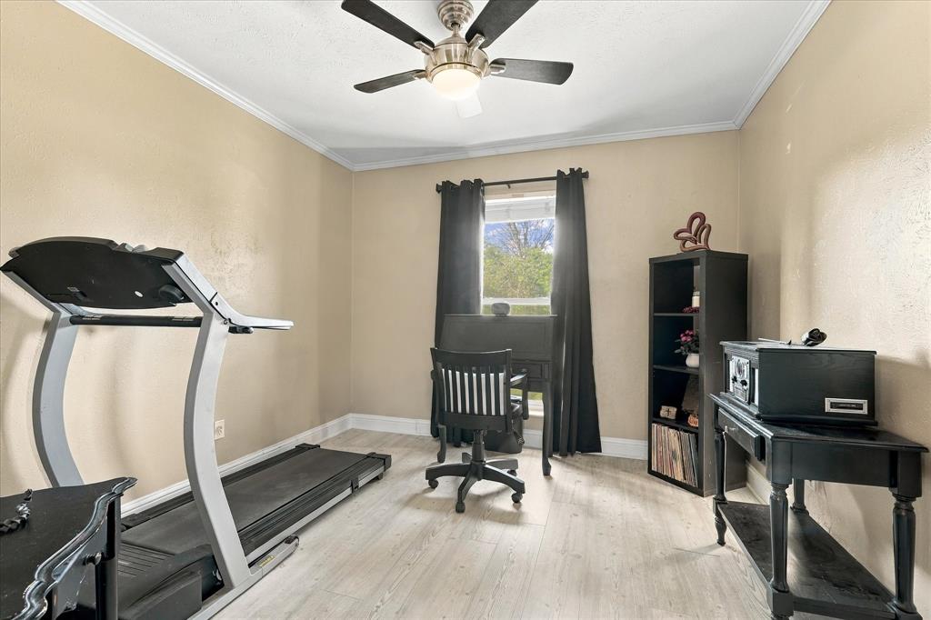 Room featuring wood-finish flooring, a central ceiling fan with integrated lighting, and a window with neutral wall finishes