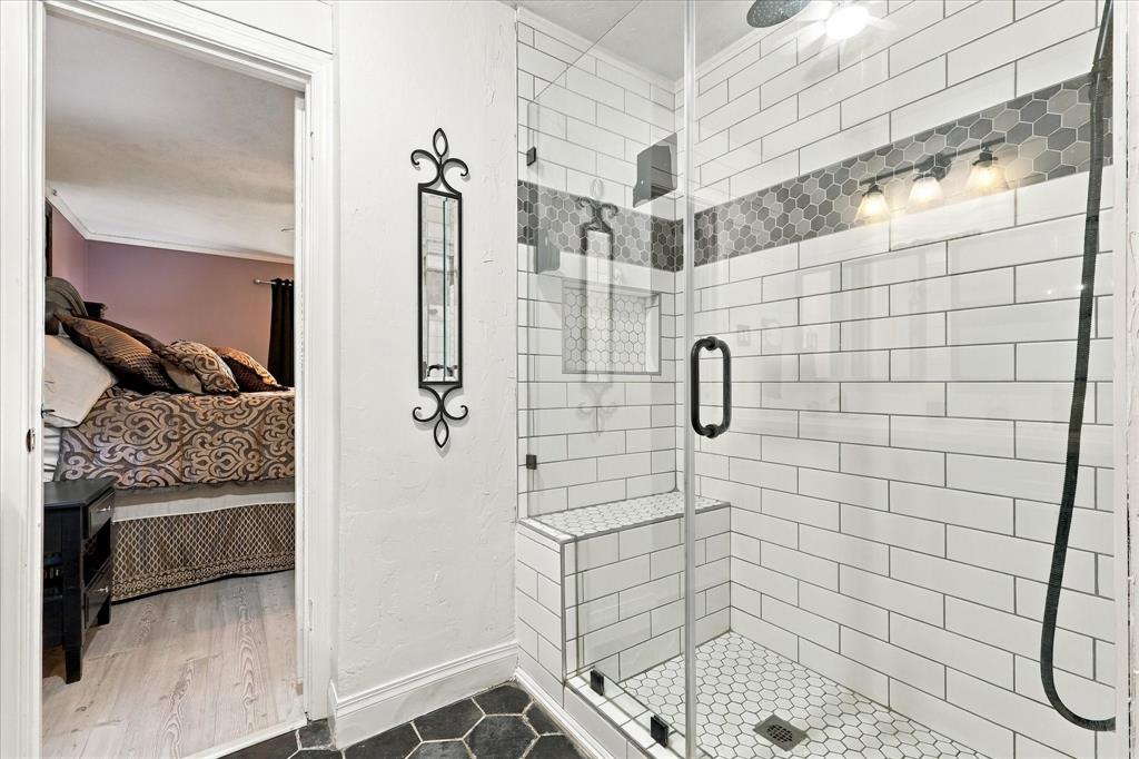 Walk-in shower featuring subway tile surround, built-in bench, hexagon tile flooring, integrated tile niche, and frameless glass enclosure