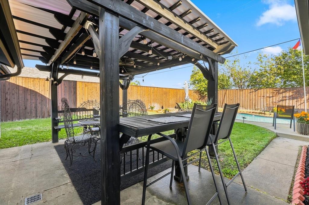 Outdoor living space featuring a wood-frame pergola, concrete patio, swimming pool, and wood privacy fencing