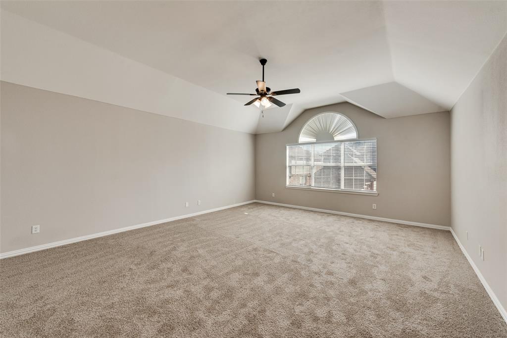 Vaulted ceilings, neutral carpeting, and a multi-light ceiling fan