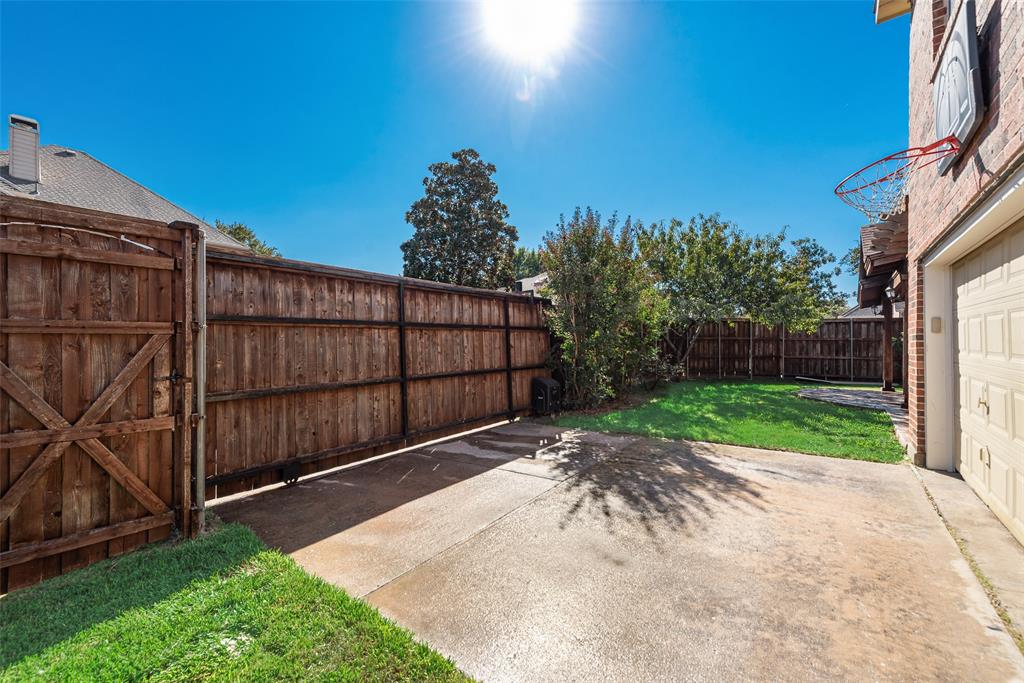 Private backyard featuring a wooden privacy fence, concrete patio, and mature trees