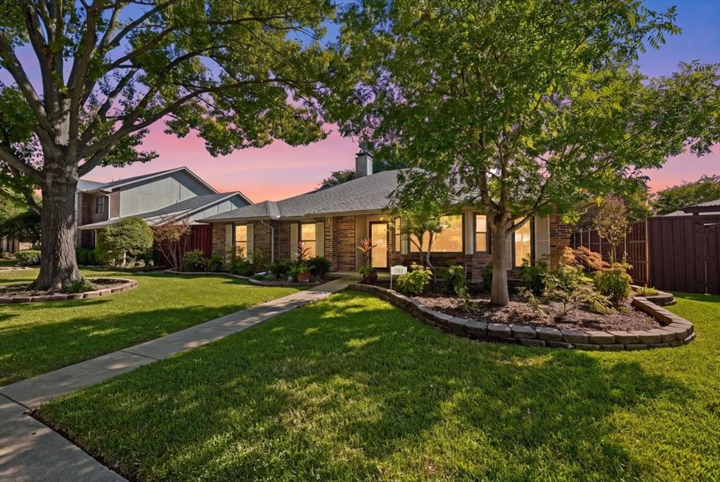 Twilight view of beautiful manicured yard with shade trees