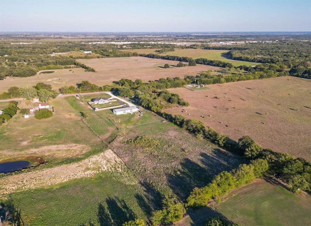 Expansive acreage featuring open pasture land, established tree lines, and a pond