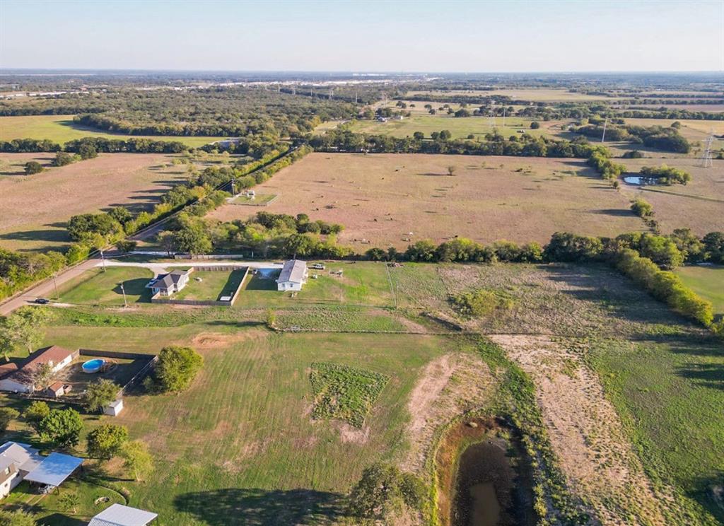 Expansive acreage featuring cleared pasture land, established tree lines, and a private pond